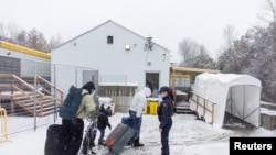 Sebuah keluarga menyeberang menuju Kanada melewati Roxham Road, titik penyeberangan tidak resmi yang terletak antara negara bagian New York dan Quebec, pada 25 Maret 2023. Mereka adalah para pencari suaka yang masuk ke Kanada. (Foto: Reuters/Carlos Osorio)