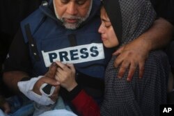 Novinar Al Jazeere Vael Al-Dahduh drži ruku svoga sina Hamze, koji je također radio za Al Jazeeru i koji je ubijen u izraelskom udaru na Rafu, u Pojasu Gaze, 7. januara 2024.