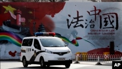 资料照：一辆警车驶过北京街头一堵宣传中国法治的宣传墙。（2016年12月28日）