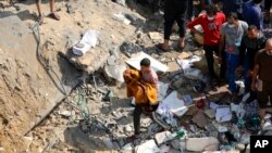 A Palestinian man carries a dead child that was found under the rubble of a destroyed building, following Israeli airstrikes in Jabaliya refugee camp, northern Gaza Strip, Nov. 1, 2023.