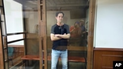 FILE — Wall Street Journal reporter Evan Gershkovich stands in a glass cage in a courtroom at the Moscow City Court in Moscow, Russia, June 22, 2023. The reporter is one of several Americans and dual citizens being held in Russia.