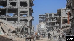 ผู้พลัดถิ่นชาวปาเลสไตน์ขนย้ายข้าวของส่วนตัวด้วยรถลากด้วยม้า ผ่านซากอาคารที่ถูกอิสราเอลถล่มในเมืองคานยูนิส ทางใต้ของฉนวนกาซ่า เมื่อ 6 มี.ค. 2567