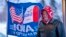 FILE - A man stands next to a flag that reading "Iowa for Trump" in Urbandale, Iowa, Jan. 11, 2024. Voters in the state are participating in caucuses on Jan. 15, 2024, that launch the Republican presidential nomination process.