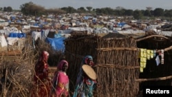 FILE - Sudanese women, who fled the conflict in Geneina in Sudan's Darfur region, walk beside makeshift shelters in Adre, Chad, Aug. 5, 2023. 
