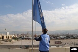 An employee at the United Nations Relief and Works Agency (UNRWA) for supporting Palestinians lowers the U.N. flag on the roof of the organization's regional offices in the Lebanese capital of Beirut, Nov. 13, 2023.