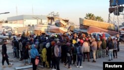 FILE - Migrants wait at Sfax port, after being stopped by Tunisian coast guard at sea during their attempt to cross to Italy, Apr. 26, 2023. 