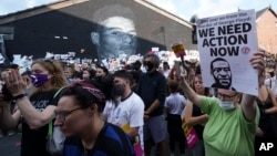 A protester holds-up a banner bearing an image of George Floyd during an anti-racism protest on the wall of the Coffee House Cafe on Copson Street, in Withington, Manchester, England, Tuesday July 13, 2021. (AP Photo/Jon Super, File)