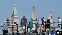 Tourists walk toward St. Mark's Square in Venice, July 31, 2023. UNESCO is recommending that Venice be placed on the list of World Heritage in Danger, as "insufficient" measures have been taken to protect the city against tourism and climate change.