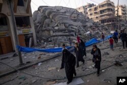 Palestinci hodaju pored ruševina zgrade uništene u izraelskom vazdušnom udaru, u gradu Gaza, 8. oktobra 2023.