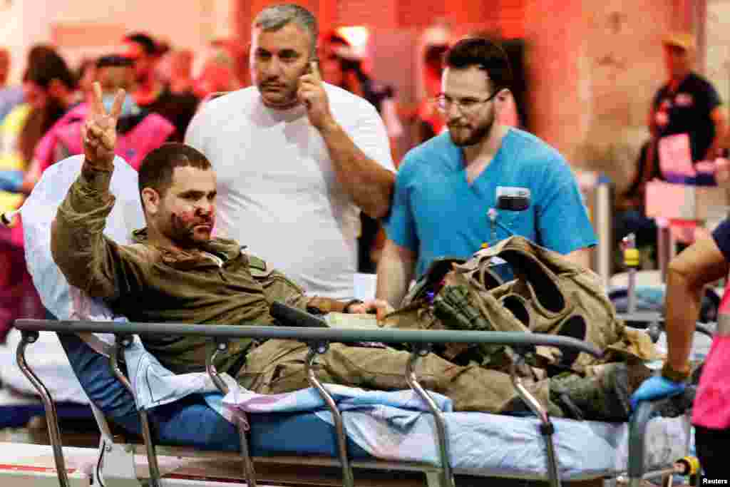 An injured Israeli officer gestures as he arrives at a hospital in Ashkelon, Oct. 7, 2023.