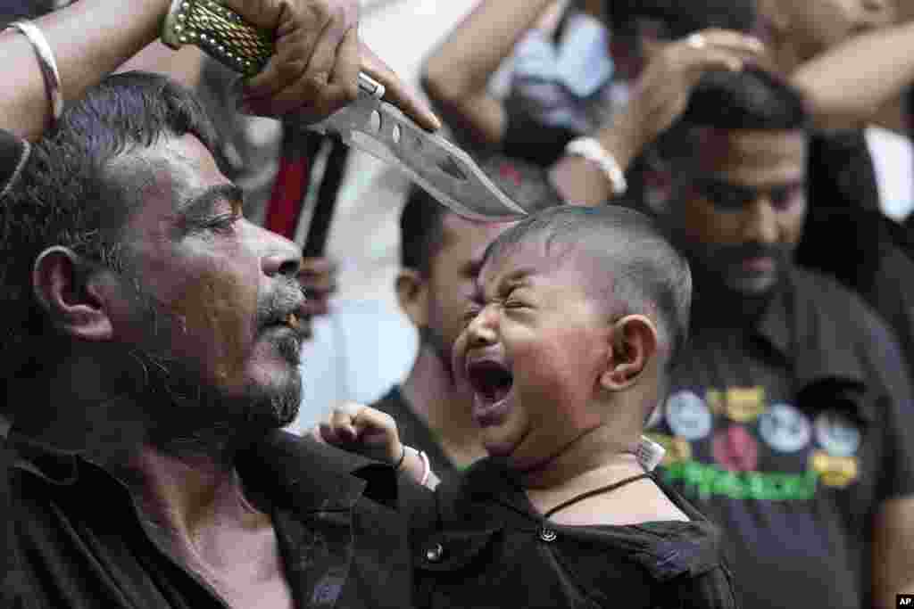 A Shiite Muslim touches the forehead of a child with the point of his knife during a Muharram procession in Ahmedabad, India, July 26, 2023. 