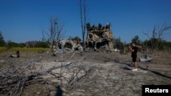 A man takes a picture of a crater that appeared during a Russian missile strike, outside of Kyiv, Ukraine, Aug. 18, 2024. 