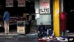 FILE - An elderly street vendor displays clothes for sale next to a meat shop in an outdoor market in Fatih district of Istanbul, Turkey, May 23, 2023.