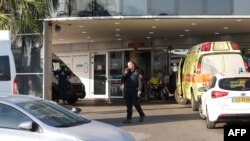 An Israeli policeman talks on the phone outside the emergency entrance to the Sheba Medical Centre in Ramat Gan city on July 15, 2023, after Prime Minister Benjamin Netanyahu was hospitalized.