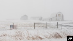 An American flag is seen fixed to a farm fence along U.S. Highway 20 during a blizzard near Galva, Iowa, Jan. 13, 2024. 