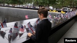미국 뉴욕 맨해튼 구에 있는 9/11 기념관에서 세계무역센터 테러를 기리는 행사 중 한 소년이 미국 국기를 꽂고 있다. (자료화면)