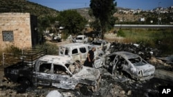 A Palestinian man inspects scorched cars, including some junked for spare parts, in the West Bank village of A Laban al-Sharkiyeh, June 21, 2023.
