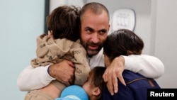 26일 이스라엘 남성이 하마스 인질에서 풀려난 아내와 자녀들을 안고 있다.