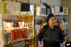 Chad Lee explains his role as a Hmong shaman in front of the altars in his house in St. Paul, Minnesota, Nov. 16, 2023. For New Year, the altars will be redecorated with new paper designs.