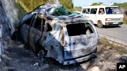 A minibus passes the attacked car that was used by the senior Hezbollah commander Wissam Tawil, who was killed by an Israeli airstrike the previous day, in Kherbet Selem village, south Lebanon, Jan. 9, 2024.