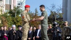 In this photo provided by the Ukrainian Presidential Press Office, Ukrainian President Volodymyr Zelenskyy, center right, awards a serviceman during an event for marking Statehood Day in Mykhailivska Square in Kyiv, July 28, 2023.