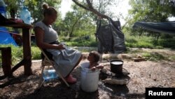 Venezuelan asylum seeker Alejandra Pena bathes her son Natanael, 1, in a plastic bucket next to their tent, while they wait to attempt to cross into the U.S., at a makeshift camp, in Matamoros, Mexico, June 20, 2023.