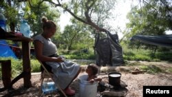 Venezuelan asylum-seeker Alejandra Pena, 34, bathes her son Natanael, 1, in a plastic bucket next to their tent, while they wait to attempt to cross into the U.S. at a makeshift camp in Matamoros, Mexico, June 20, 2023.