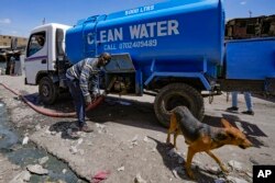 FILE - A water vendor fills up reservoir water tanks to be sold to residents in Athi River, Machakos county, Kenya, Oct. 17, 2023.