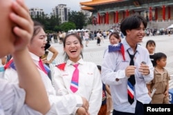 Students wear Taiwan flag on their shoulders laugh at an army recruitment event in Taipei, Taiwan, July 1, 2023.