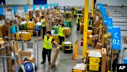 FILE - Employees load packages on carts at an Amazon delivery station, July 16, 2024, in South Gate, Calif. "The economy has been very strong for a couple of years," said Kimberly Clausing of the Peterson Institute for International Economics.