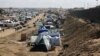 Palestinians displaced by the Israel air and ground offensive on the Gaza Striptake shelter near the border fence with Egypt in Rafah, Jan. 24, 2024. 