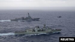 资料照片：美国海军导弹驱逐舰“钟云号”与加拿大皇家海军护卫舰“蒙特利尔号”在南中国海进行演习期间并肩航行。（2023年5月30日）