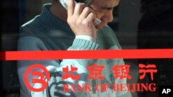 រូបឯកសារ៖ រូបភាពកាលពីថ្ងៃទី២៩ ខែមករា ឆ្នាំ២០០៥ បង្ហាញបុរសជនជាតិចិនម្នាក់និយាយទូរស័ព្ទក្នុងអគារដែលមានសរសេរថា Bank of Beijing ក្នុងទីក្រុងប៉េកាំង ប្រទេសចិន។ 