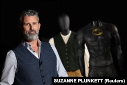 สตีเฟน เลน ผู้ก่อตั้งและซีอีโอของ Propstore ผู้จัดประมูลของที่ระลึกจากกองถ่ายภาพยนตร์ ยืนถ่ายรูปพร้อมเสื้อผ้าจาก ''ไททานิค'' และ "แบทแมน"