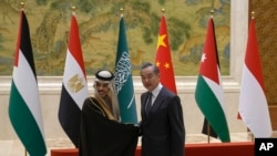 Menteri Luar Negeri China Wang Yi (kanan) dan Menteri Luar Negeri Arab Saudi Faisal bin Farhan Al Saud berjabat tangan ketika bertemu di Beijing, pada 20 November 2023. (Foto: AP/Andy Wong)