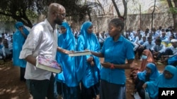 This handout picture taken on Oct. 25, 2023, shows Abdullahi Mire, left, winner of the U.N. refugee agency's prestigious Nansen Award distributing books to refugee students in Kenya's Dadaab refugee camp. (AFP Photo/UNHCR)