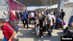 Warga Palestina berkewarganegaraan ganda berjalan di Rafah, Jalur Gaza selatan, perbatasan Rafah-Mesir, dengan harapan mendapat izin meninggalkan Gaza, di tengah konflik Israel-Hamas, 1 November 2023. (REUTERS/ Arafat Barbakh)