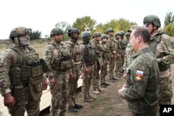 Russian Security Council Deputy Chairman Dmitry Medvedev, front right, speaks to Russian military members during his visit to a military training range in a Russian-occupied part of Ukraine's Donetsk region on Sept. 15, 2023. (Sputnik via AP)