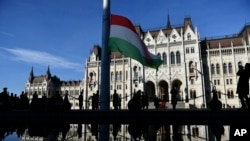 FILE - Pengibaran bendera di depan Parlemen Hungaria di Budapest, 23 Oktober 2022. (Anna Szilagyi/AP)