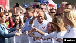 Donald Tusk, the leader of the largest opposition grouping Civic Coalition (KO) and Rafal Trzaskowski, mayor of Warsaw stand in front of the national flag during the 'Marsz Miliona Serc' rally, in Warsaw, Oct. 1, 2023.
