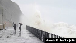People stand on the promenade in Folkestone, England, Nov. 2, 2023, as Storm Ciaran brings high winds and heavy rain to the southern coast of England.