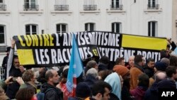 People hold a banner reading 'Against antisemitism, the racisms and the far right' as they take part in a gathering organized by LFI party for a wreath-laying ceremony on the sidelines of a rally against anti-semitism, Paris, Nov. 12, 2023.
