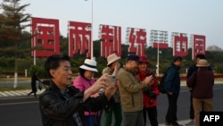 资料照：中国福建厦门竖立起一个台湾金门岛可以看到的“一国两制统一中国”的大型标语牌，旅游者在前拍照。（2024年1月12日）