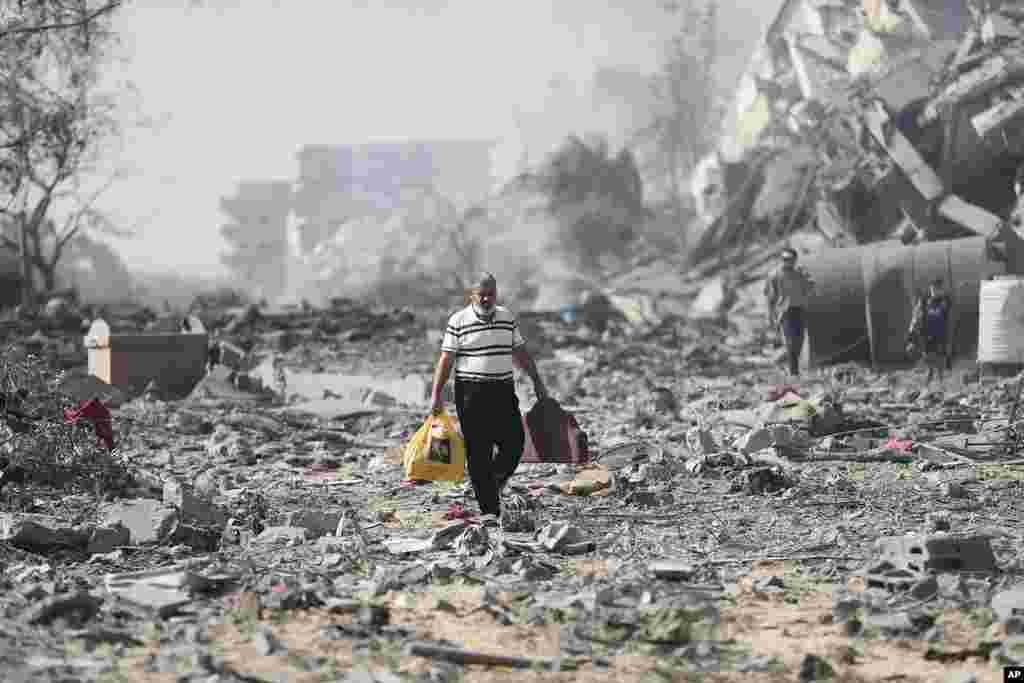 Palestinians walk by the buildings destroyed in the Israeli bombardment on al-Zahra, on the outskirts of Gaza City.&nbsp;(AP Photo/Ali Mahmoud)
