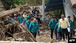 ປະທານາທິບໍດີເກົາຫຼີໃຕ້ ທ່ານຢຸນ ຊຸກ ໂຢລ (ກາງ), ຍ່າງຜ່ານກອງຕົ້ນໄມ້ທີ່ຫັກລົ້ມ ຢູ່ໃນໝູ່ບ້ານ ເຊິ່ງເປັນຂົງເຂດທີ່ມີບ້ານເຮືອນຫຼາຍກວ່ານຶ່ງສ່ວນສາມ ຖືກທໍາລາຍດ້ວຍສະພາບດິນເຈື່ອນ ແລະສອງຄົນຍັງຄົງຫາຍສາບສູນ, ໃນເມືອງເຢຊິນ, ວັນທີ 17 ກໍລະກົດ 2023.