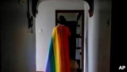 FILE - A gay Ugandan man covers himself with a pride flag as he poses for a photograph in Uganda on March 25, 2023. The U.N. Human Rights Committee condemned Uganda’s Anti-Homosexuality Act on July 26, 2023.