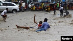 FILE - A man attempts to rescue a boy from raging floodwaters following heavy rains in Mogadishu, Somalia, Nov. 9, 2023. Farah Omar Nur, the secretary general of the Federation of Somali Journalists, says environmental journalism is not easy, especially in Somalia.