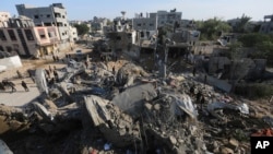 Warga Palestina melihat bangunan-bangunan yang hancur akibat serangan Israel di Jalur Gaza di Rafah, Senin, 4 Desember 2023. (AP Photo/Hatem Ali)