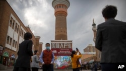 Sejumlah wisatawan berfoto di Urumqi di Wilayah Otonomi Xinjiang Uyghur dalam lawatan untuk jurnalis asing yag disponsori Pemerintah China, 21 April 2021. (Foto: Mark Schiefelbein/AP Photo)