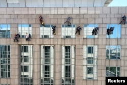 清洗高层建筑玻璃的工人继续在北京高温天气中工作。（2023年6月22日）